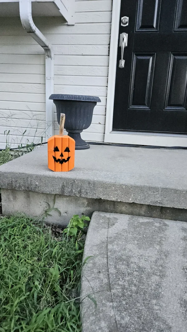 Small Orange Jack-O-Lantern made from 2x4 and a natural branch as stem.