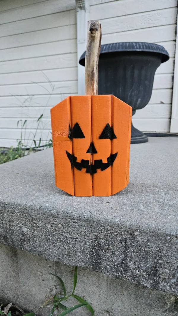 Small Orange Jack-O-Lantern made from 2x4 and a natural branch as stem.