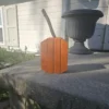 Small Orange Jack-O-Lantern made from 2x4 and a natural branch as stem.